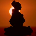Person in Meditationspose mit sanftem Sonnenuntergangslicht