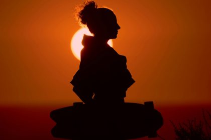 Person in Meditationspose mit sanftem Sonnenuntergangslicht
