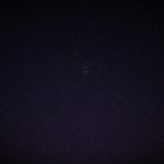 Sternenhimmel mit Wolken und Mondlicht ueber einer Berglandschaft