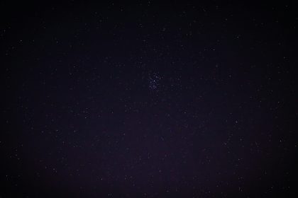 Sternenhimmel mit Wolken und Mondlicht ueber einer Berglandschaft