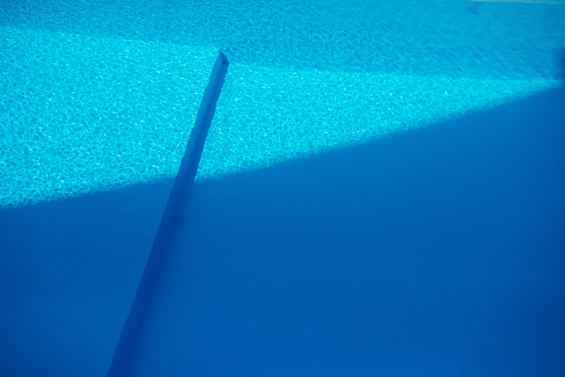 Ruhige Wasseroberfläche mit konzentrischen Ringen, in denen sich das Licht in feinen Streifen bricht