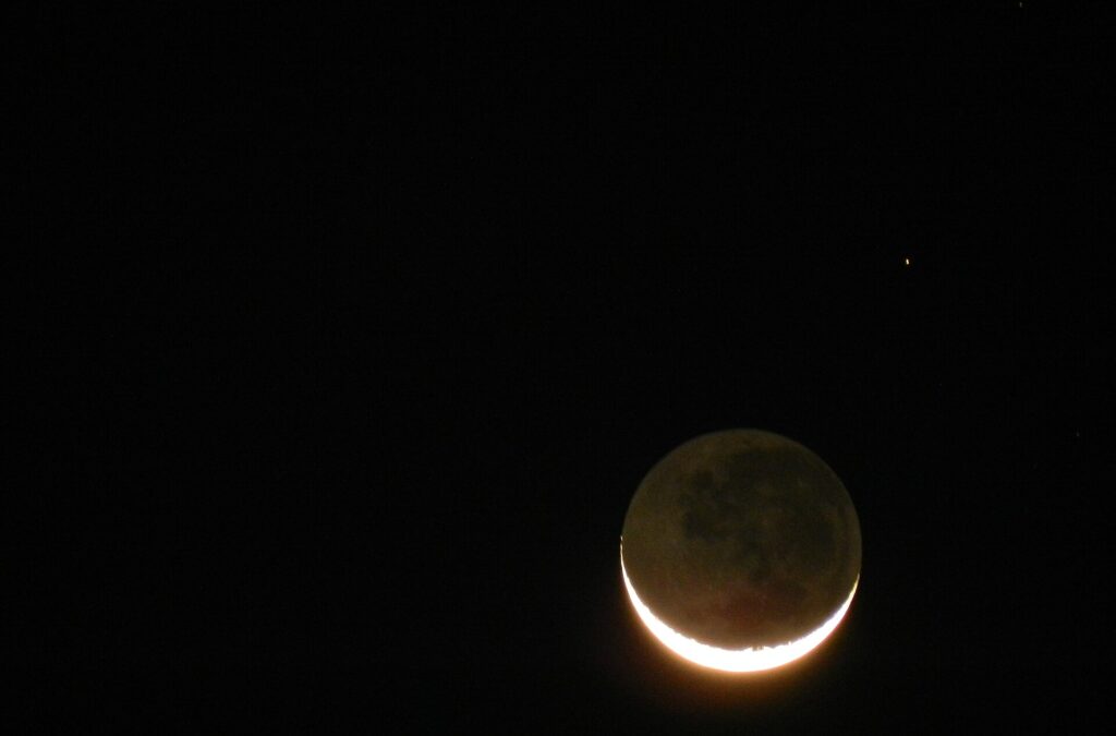 Helle Sichel mit schwach grau leuchtender restlicher Mondscheibe vor tiefblauem Abendhimmel