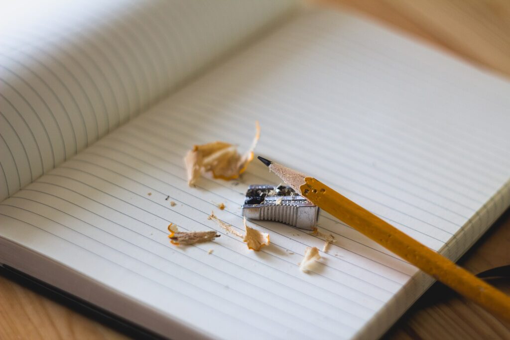 Aufgeschlagenes Notizheft mit handschriftlichen Zeilen und ein Bleistift auf einem Holztisch