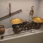 Alte Balkenwaage aus Metall mit zwei Schalen steht vor einem hellen Hintergrund, die Zunge in Ruhelage