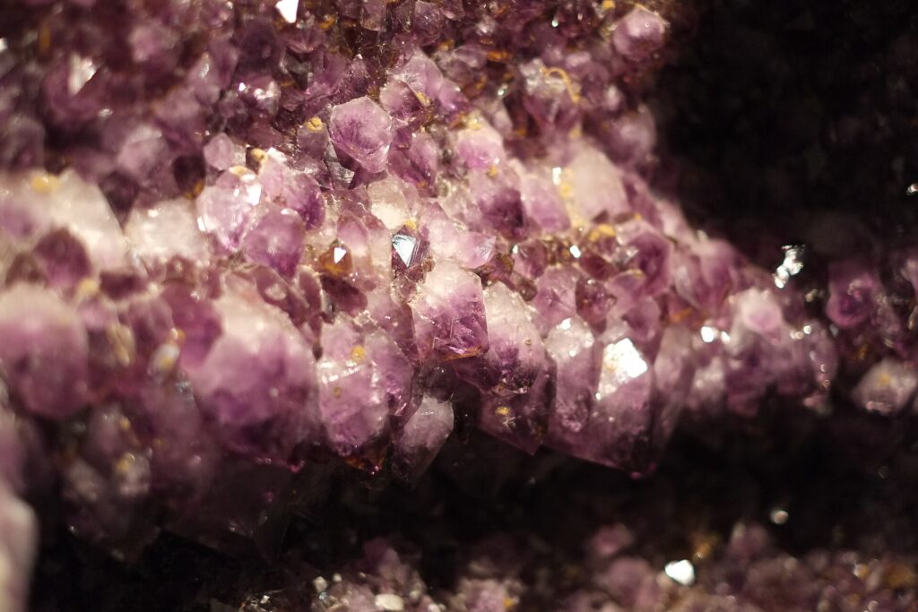 Violette Kristallstufe mit vielen spitzen Kristallen auf grauem Muttergestein