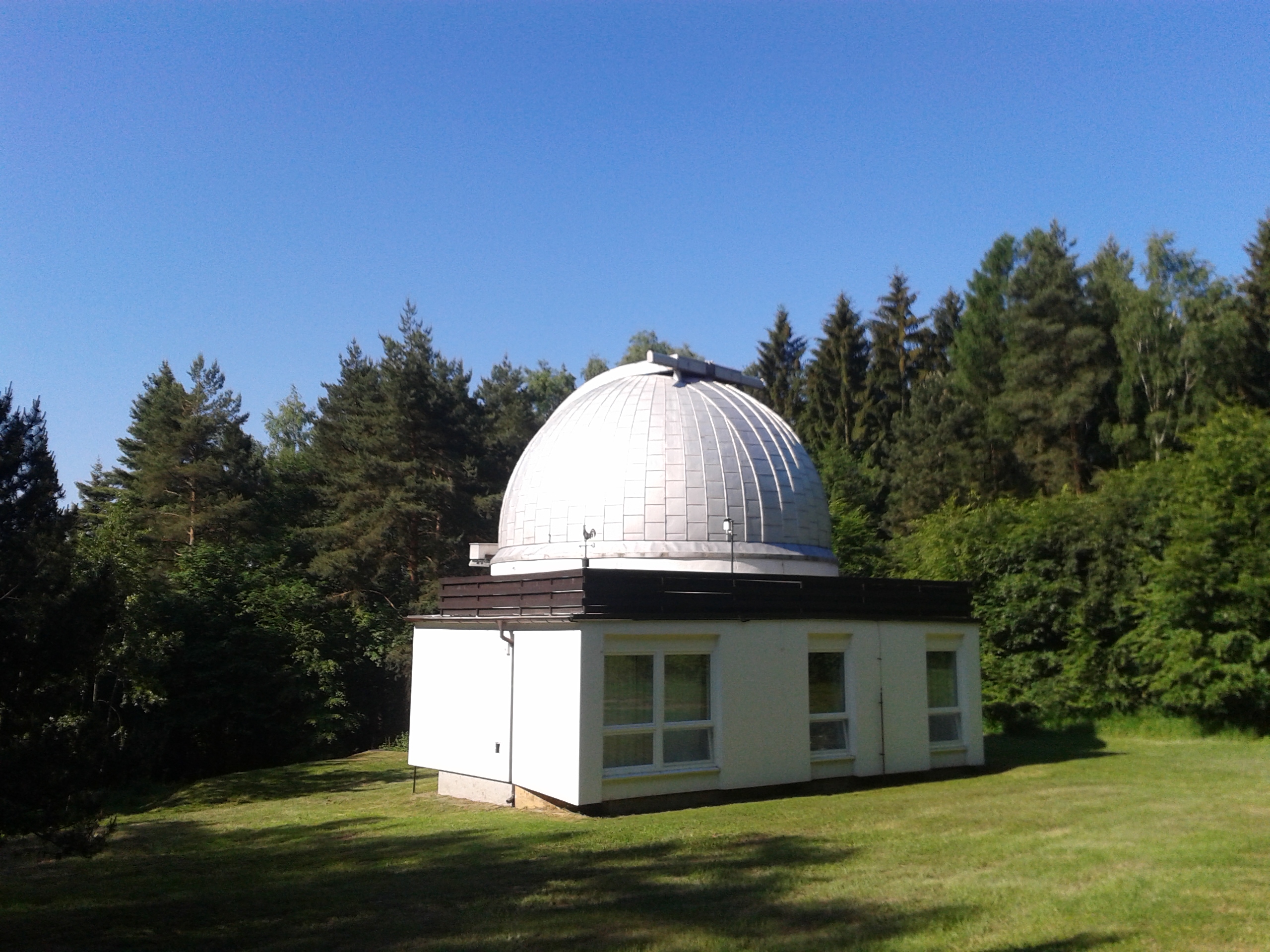Kuppel eines Observatoriums bei Nacht mit geöffnetem Spalt und Sternen darüber