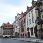 Historische astronomische Uhr mit mehreren Zeigern und beschrifteten Ringen an einer Fassade