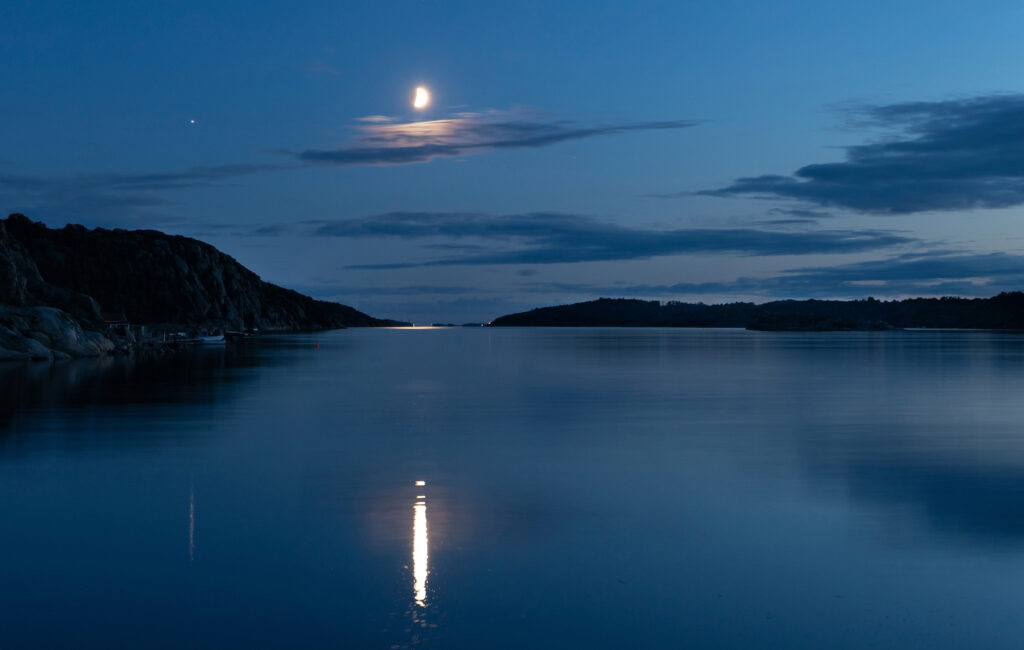 Aufgehender Mond über einem abgeernteten Feld in der Dämmerung